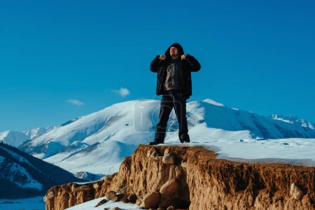Foto de Joven excursionista de pie en el acantilado en el fondo de la montaña en invierno - Imagen libre de derechos