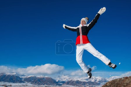 Foto de Mujer feliz turista saltando en las montañas de fondo en invierno - Imagen libre de derechos