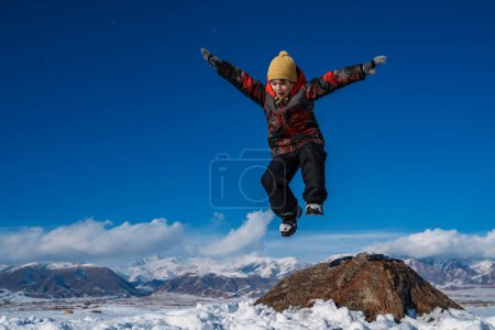 Photo for Happy boy jumping on mountains background in winter - Royalty Free Image