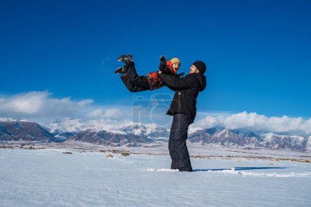 Photo for Father having fun with his son on mountains background in winter - Royalty Free Image