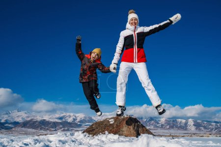 Foto de Feliz joven mujer e hijo saltando en las montañas fondo de invierno - Imagen libre de derechos