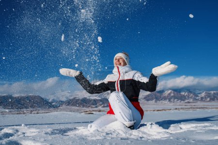 Foto de Joven mujer feliz tirar nieve en invierno montañas fondo - Imagen libre de derechos