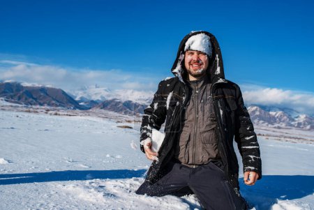 Foto de Retrato de invierno del hombre con nieve en la cara sobre el fondo de las montañas - Imagen libre de derechos