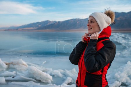 Photo for Young woman tourist on the shore of frozen lake in winter - Royalty Free Image