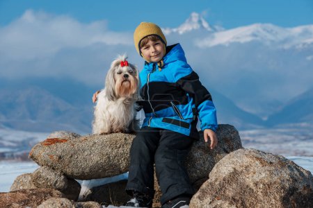 Foto de Niño con shih tzu perro retrato de invierno en las montañas de fondo - Imagen libre de derechos