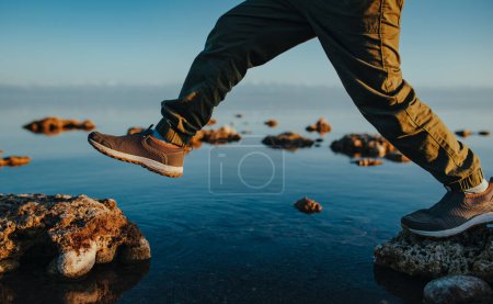 Photo for Boy walking on stones in the lake close-up view - Royalty Free Image