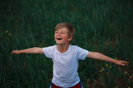 Foto de Lindo retrato de niño riendo en el campo de verano verde - Imagen libre de derechos