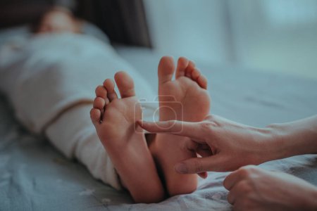 Téléchargez les photos : La main de la femme touche le pied de l'enfant endormi - en image libre de droit