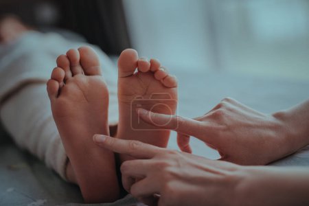 Photo for Mother tickles sleeping child feet - Royalty Free Image