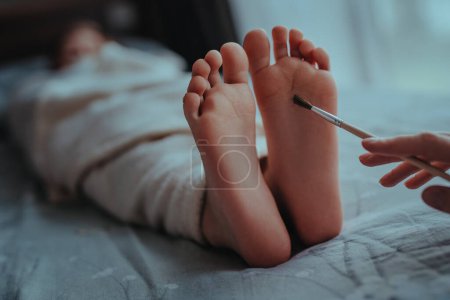 Foto de La mano de la mujer cepilla los pies del bebé dormido - Imagen libre de derechos