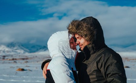 Foto de Joven pareja romántica abrazando en las montañas de fondo en invierno - Imagen libre de derechos