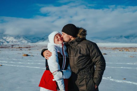Téléchargez les photos : Romantique jeune couple embrasser sur fond de montagnes en hiver - en image libre de droit