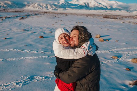 Téléchargez les photos : Romantique jeune couple embrassant sur fond de montagnes en hiver - en image libre de droit