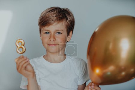 Foto de Retrato de niño guapo con vela de cumpleaños 8 y globo - Imagen libre de derechos