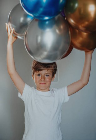 Foto de Retrato de un chico guapo sosteniendo globos sobre su cabeza - Imagen libre de derechos