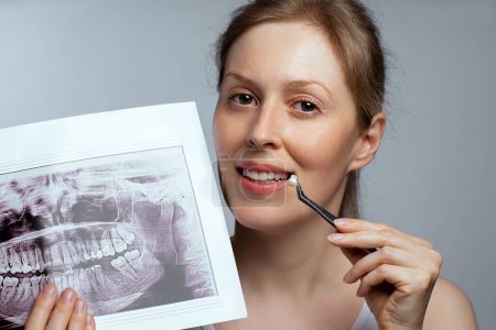 Foto de Retrato de mujer joven sosteniendo una corona dental y rayos X, concepto de odontología - Imagen libre de derechos