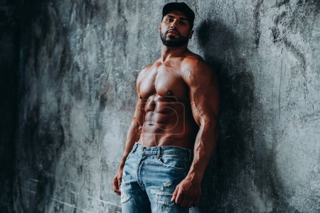 Téléchargez les photos : Jeune homme fort bodybuilder en chapeau sur fond de mur de pierre - en image libre de droit