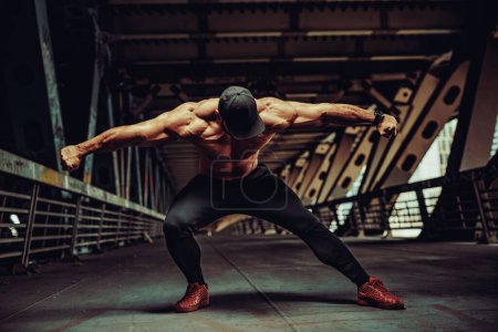 Téléchargez les photos : Jeune homme fort bodybuilder posant sur fond industriel urbain - en image libre de droit