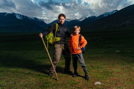Foto de Man hiker with his son standing in the mountains at dusk - Imagen libre de derechos
