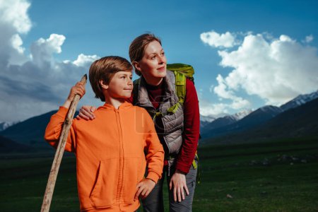 Téléchargez les photos : Jeune femme avec son fils debout dans les montagnes au crépuscule et regardant loin - en image libre de droit