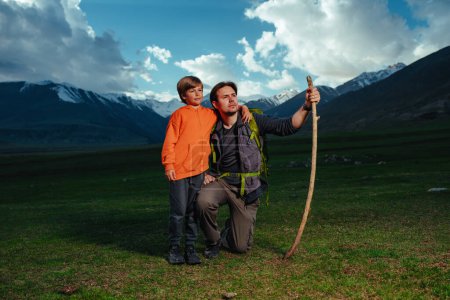 Foto de Hombre excursionista con su hijo de pie en las montañas en el crepúsculo - Imagen libre de derechos