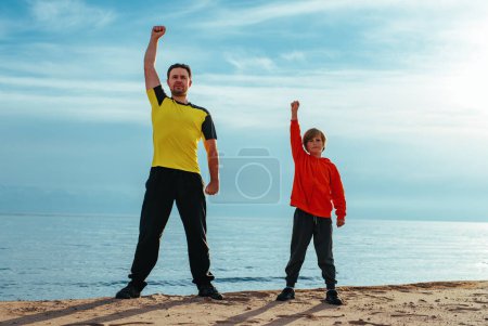 Foto de Padre e hijo haciendo ejercicios deportivos en la playa en el día de verano - Imagen libre de derechos