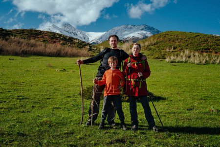 Téléchargez les photos : Randonnée en famille debout dans les montagnes sur un pré verdoyant - en image libre de droit