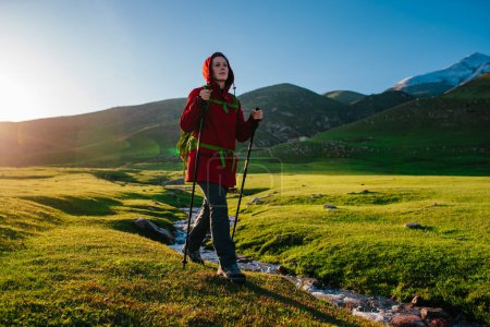 Foto de Joven turista camina a lo largo del arroyo en el pintoresco valle de la montaña en un día soleado - Imagen libre de derechos