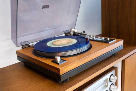Photo for Vintage Stereo Turntable Vinyl Record Player with Open Plastic Lid and Wooden Plinth Standing Above Amplifier. Home Retro Audio Sound Equipment. - Royalty Free Image
