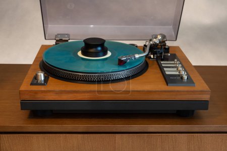Photo for Vintage Stereo Turntable Vinyl Record Player with Open Plastic Lid and Wooden Plinth Standing on Shelf. Home Retro Audio Sound Equipment - Royalty Free Image