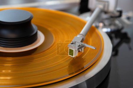 Photo for Vintage Stereo Turntable Vinyl Record Tonearm Cartridge Closeup.  Stylus Flies Above Colored Record with Clamped with Weight. - Royalty Free Image