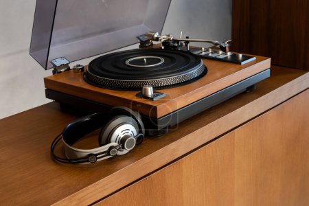Téléchargez les photos : Lecteur de disque vinyle stéréo vintage avec couvercle en plastique ouvert et écouteurs debout sur une étagère en bois. Accueil Système audio rétro avec haut-parleurs. - en image libre de droit