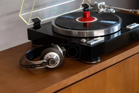 Téléchargez les photos : Lecteur de disque vinyle stéréo vintage avec couvercle en plastique ouvert et écouteurs debout sur une étagère en bois. Accueil Système audio rétro avec haut-parleurs - en image libre de droit