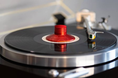 Foto de Vintage Stereo Turntable Vinyl Record Tonearm Cartridge Primer plano. Stylus vuela por encima del disco de vinilo con abrazadera de peso. - Imagen libre de derechos