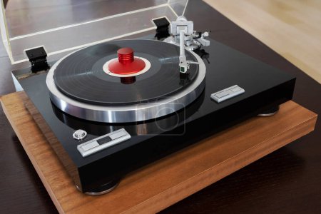 Photo for Vintage Stereo Turntable Vinyl Record Player. Red Clamp Weight Holds the Black Record - Royalty Free Image