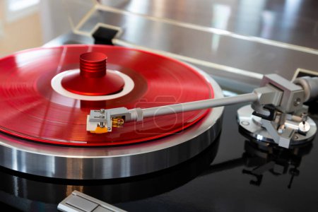 Foto de Giradiscos Estéreo Vintage Record Player Tonearm por encima de vinilo de color rojo con abrazadera roja - Imagen libre de derechos
