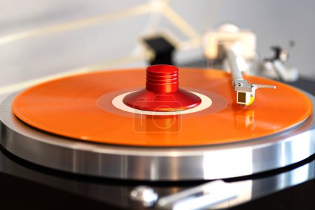Foto de Giradiscos Estéreo Vintage Record Player Tonearm por encima de vinilo de color naranja con abrazadera de peso - Imagen libre de derechos