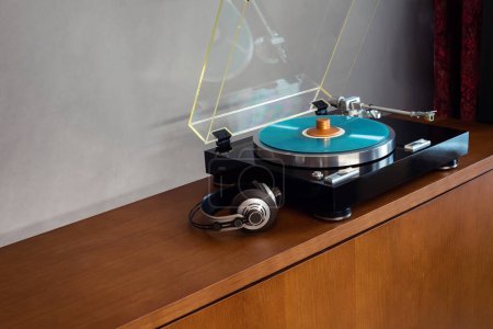 Téléchargez les photos : Tourne-disque stéréo vintage avec disque de couleur bleue, écouteurs et pince de poids noire - en image libre de droit