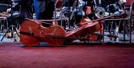 Téléchargez les photos : Image de trois instruments de musique à cordes violoncelle se trouvent sur la scène - en image libre de droit