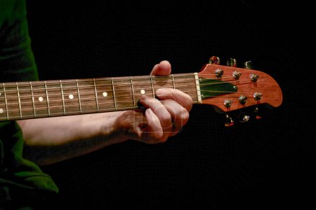 Photo for Image of a musician's fingers playing a chord on a guitar neck - Royalty Free Image