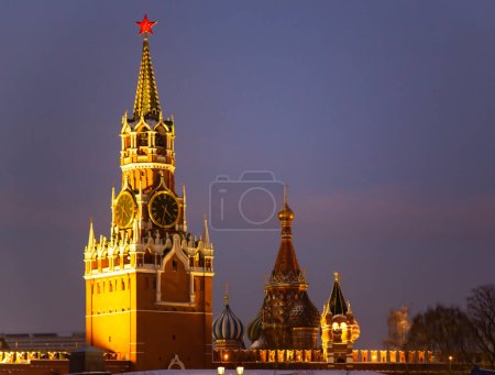 Foto de RUSIA, MOSCÚ, DICIEMBRE DE 2021 - Torre Spasskaya del Kremlin de Moscú y Catedral de la Intercesión de la Santísima Virgen María Catedral de San Basilio - vista desde el Kremlin en la iluminación de la noche - Imagen libre de derechos