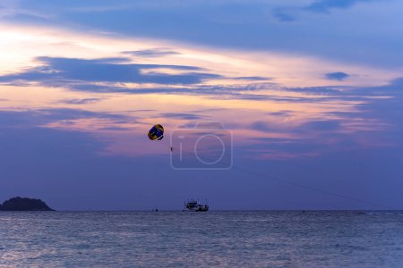 Photo for Pleasure boat with a parasailing on sunset - one of the favorite entertainment of tourists on Langkawi island, Malaysia - Royalty Free Image