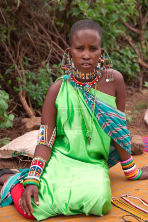Photo for AFRICA, KENYA, MAY, 2016 - Portrait of a woman of the Maasai Mara tribe with traditional dress sells braided beaded jewelry in Kenya, Africa - Royalty Free Image