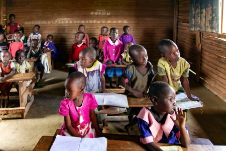 Foto de AFRICA, KENIA, MAYO DE 2016 - Niños africanos en la escuela rural dominical en Kenia, África. Origen étnico africano sentarse y estudiar en un ambiente escolar en un África - Imagen libre de derechos