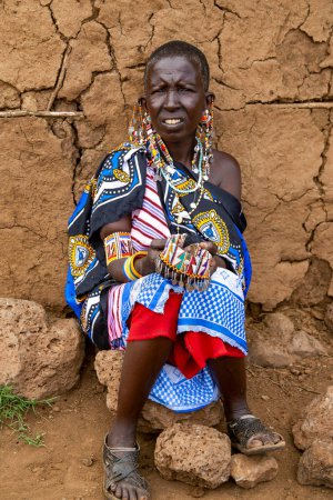 Foto de AFRICA, KENIA, MAYO DE 2016 - La mujer de la tribu Maasai nativa de retratos vende adornos hechos de cuentas. Los masai (también llamados masai) son un grupo étnico indígena africano de personas semi-nómadas ubicadas en Kenia y el norte de Tanzania.. - Imagen libre de derechos