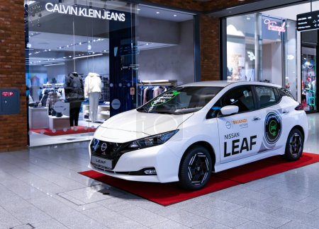 Foto de LATVIA, RIGA, FEBRERO, 2023: Modelo de automóvil eléctrico Nissan Leaf blanco en exhibición y venta en el centro comercial en Riga, Letonia. - Imagen libre de derechos