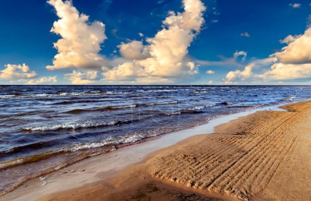 Schäumende Wellen in der Ostsee gegen den blauen Himmel mit flauschigen Wolken bei Sonnenuntergang in Jurmala, Lettland
