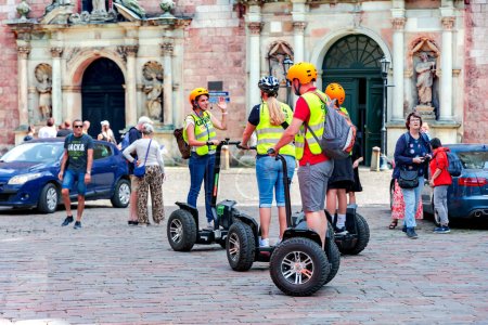 Foto de LATVIA, RIGA, 08, AGOSTO, 2023: Puesto de turistas de scooters eléctricos Segway y escuchar la historia de la guía en el casco antiguo de Riga, Letonia - Imagen libre de derechos