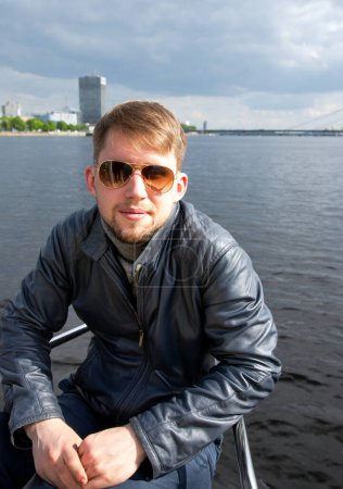 Photo for Portrait of young man in fashion sunglasses on board a yacht in the Baltic Sea, Riga. Latvia. Concept of a short holiday on the water. Relaxed Man. - Royalty Free Image