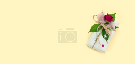 Téléchargez les photos : Ensemble de papier d'emballage et de fleurs pour fait à la main sur fond rose. Cadeaux artisanaux boîte artisanale avec bouquet de roses rouges - en image libre de droit